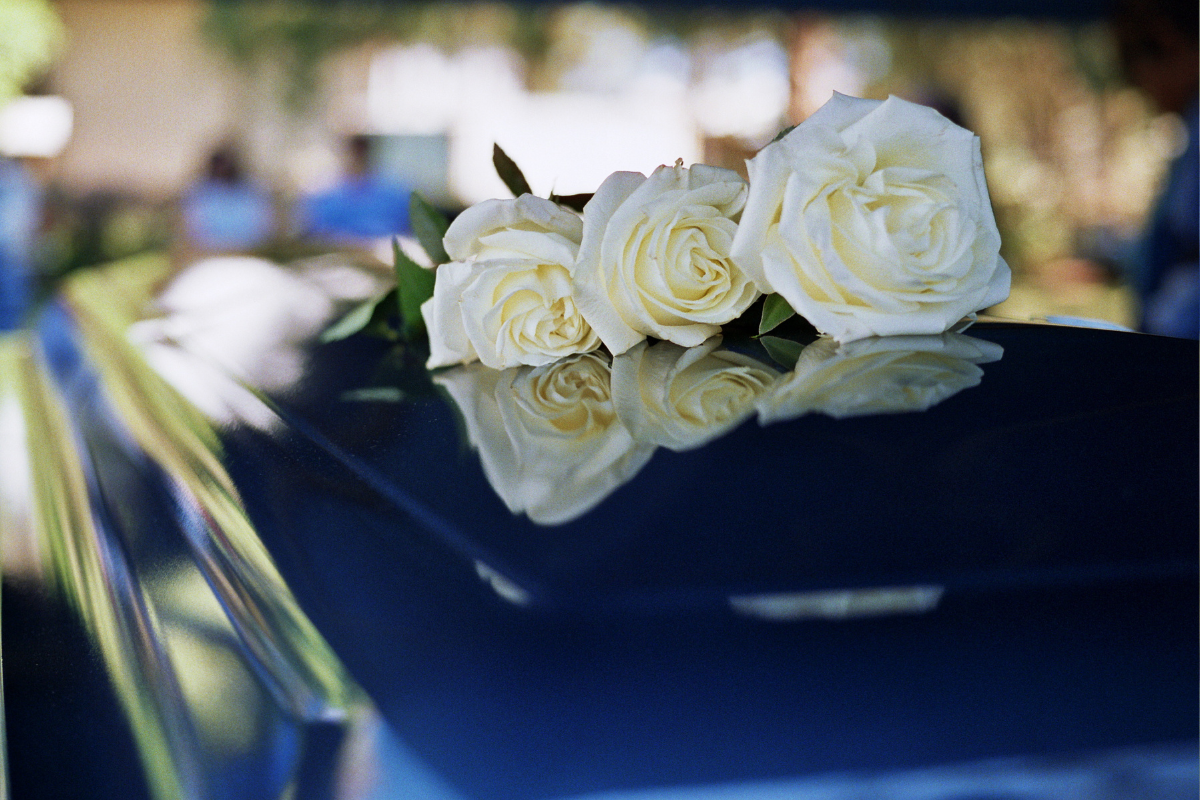A coffin with white flowers on top.