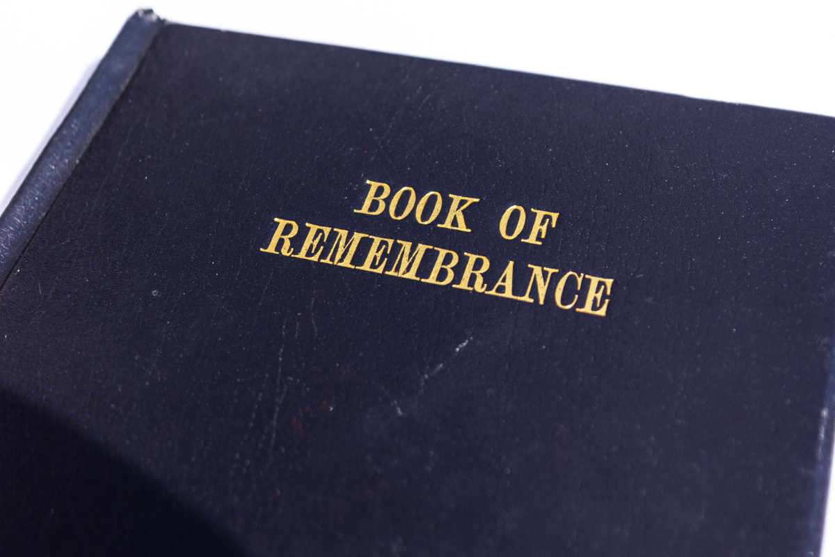 A black front cover of a book with the title in gold: BOOK OF REMEMBRANCE.
