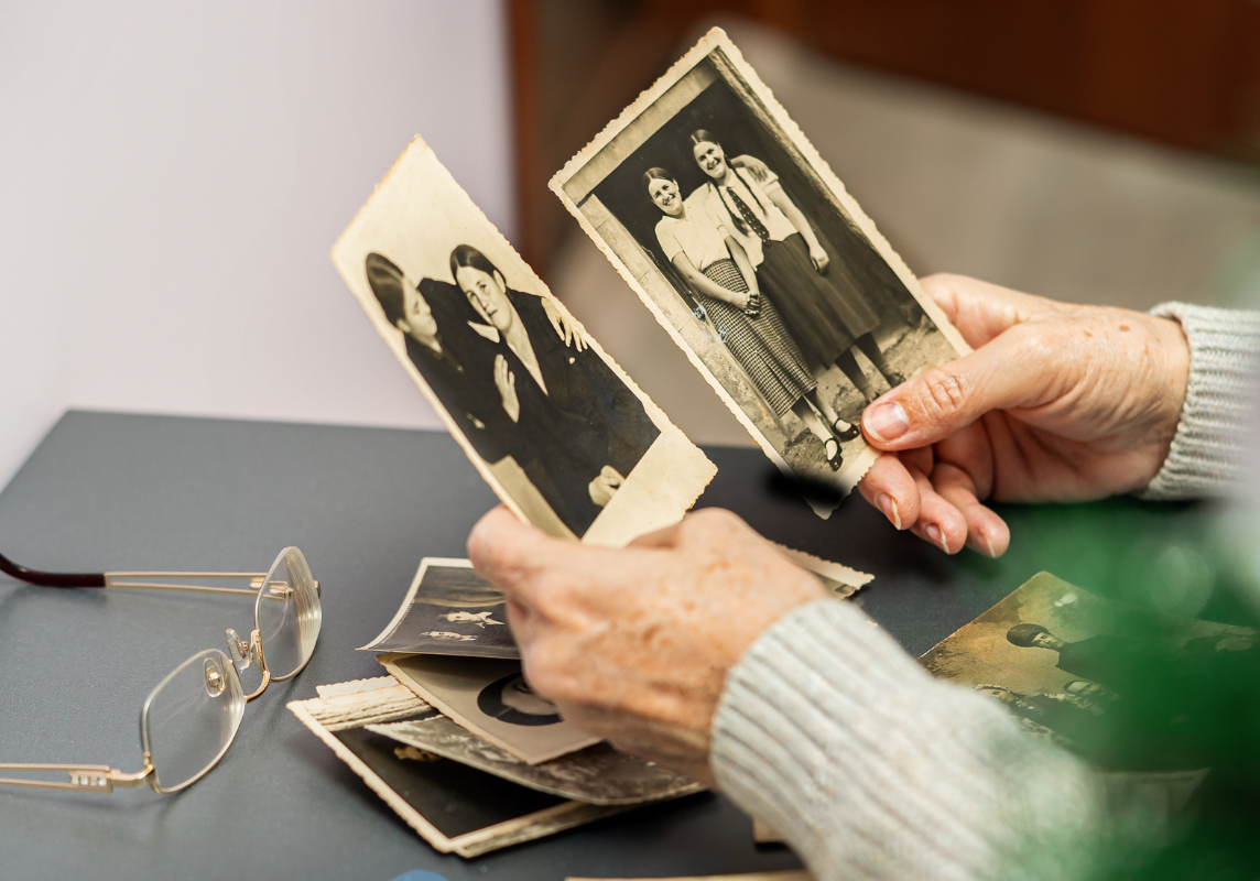 A person holding old black and white photos of a loved one.